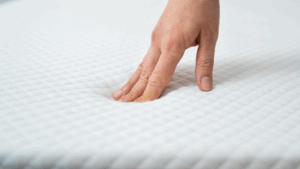 Hand touching white gel mattress
