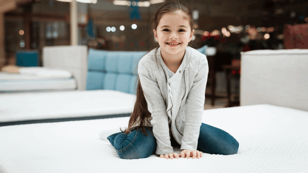 Girl sits on top of mattress in mattress store