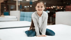 Girl sits on top of mattress in mattress store