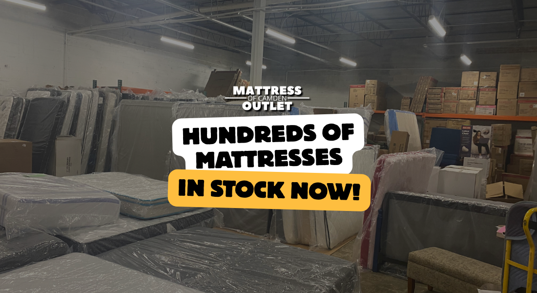 Warehouse with many mattresses in plastic wrapping; text reads Hundreds of mattresses in stock now!.
