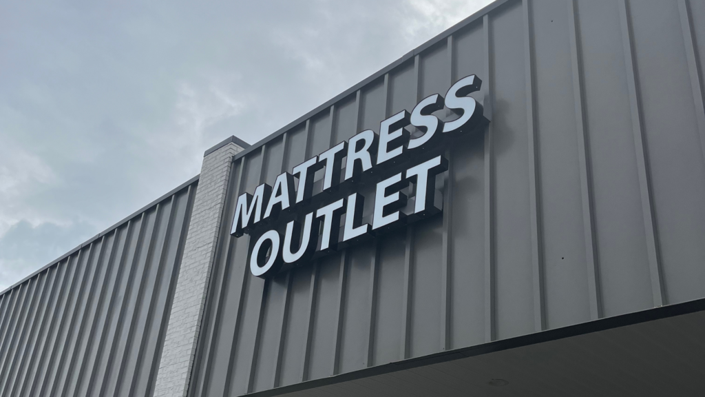A building with a large sign that reads Mattress Outlet on its exterior wall.