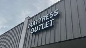 A building with a large sign that reads Mattress Outlet on its exterior wall.